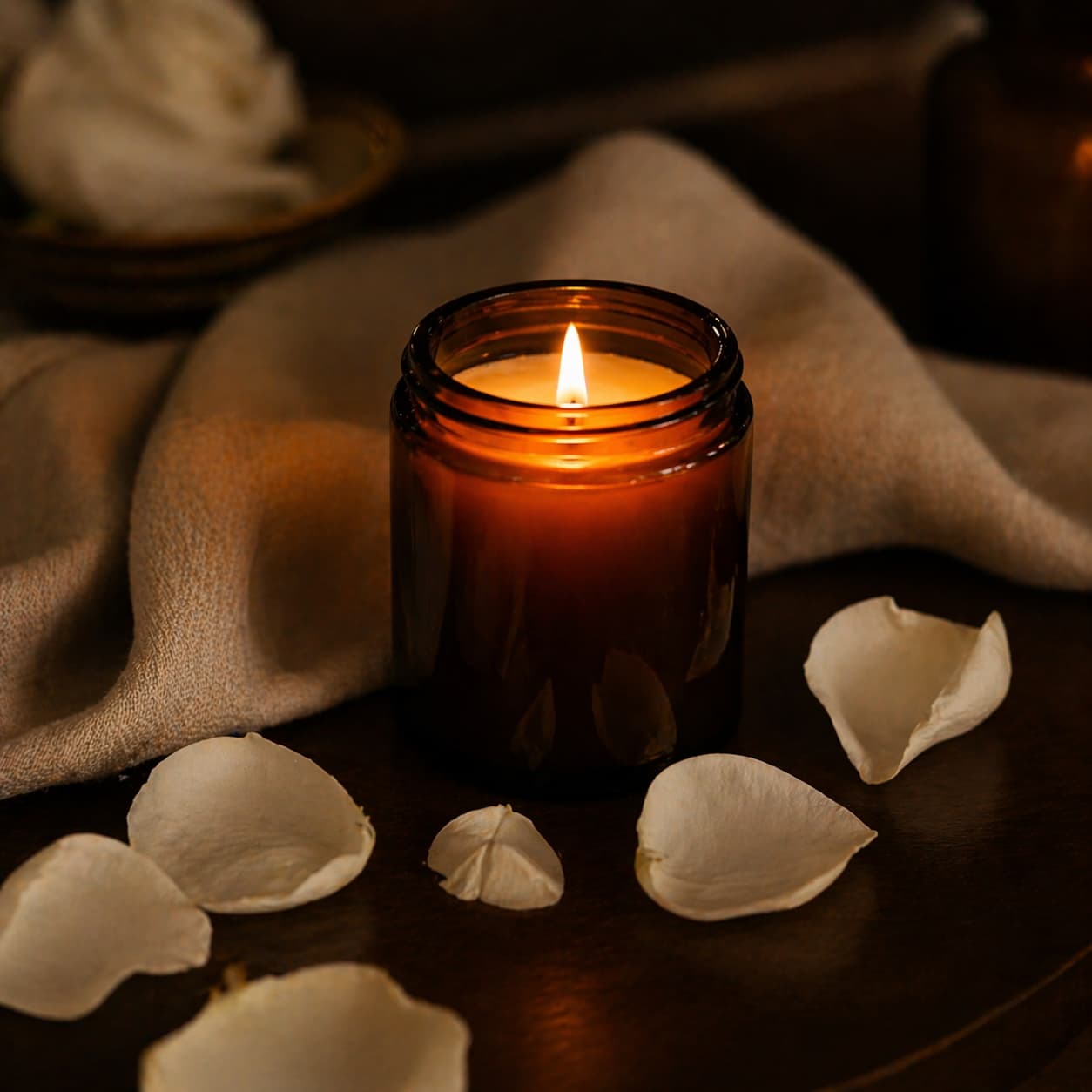 A single lit candle surrounded by rose petals in a warm spa ambience