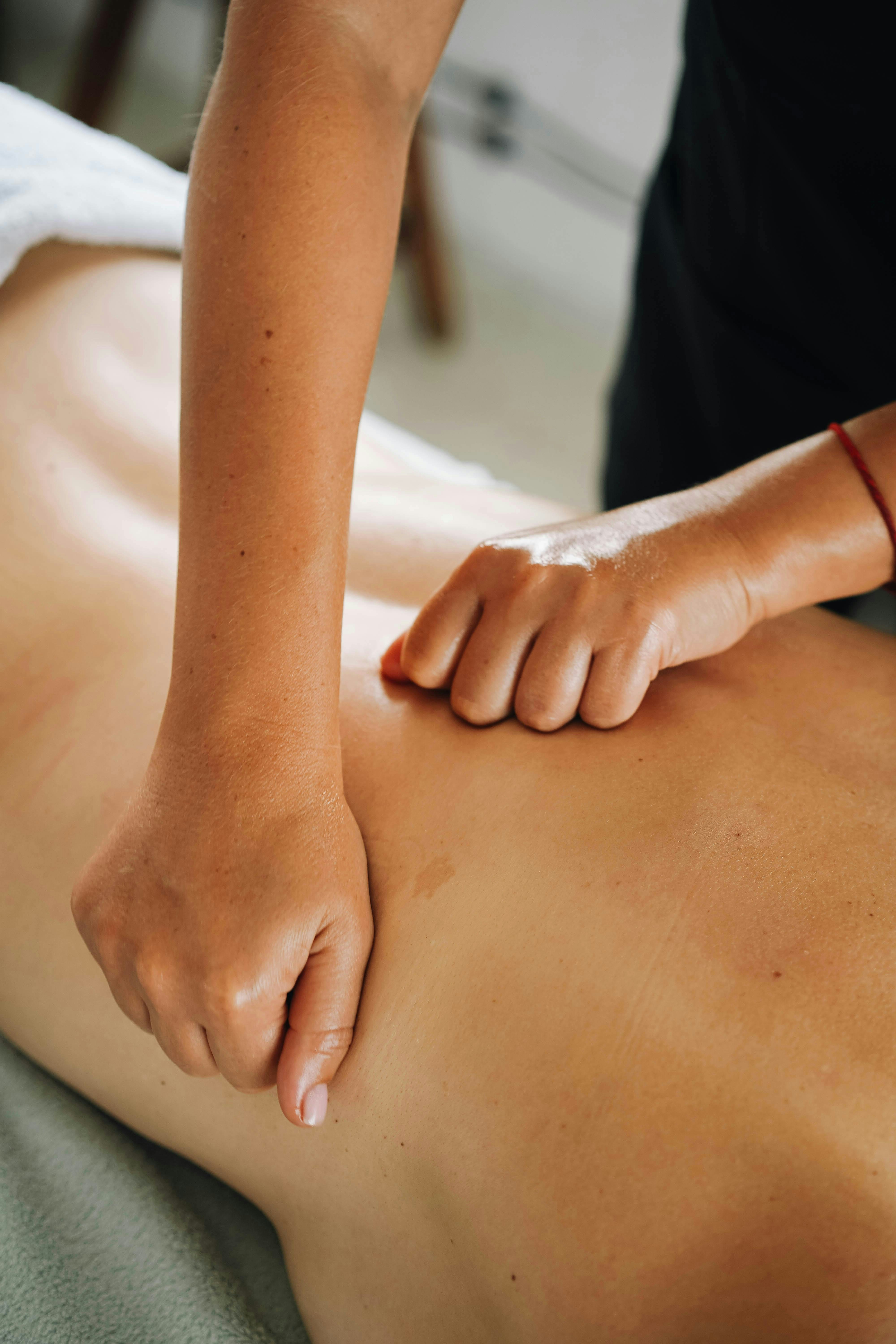 Therapist's hands performing a deep tissue back massage on a client